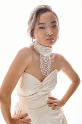 confident asian young bride in elegant necklace and dress posin